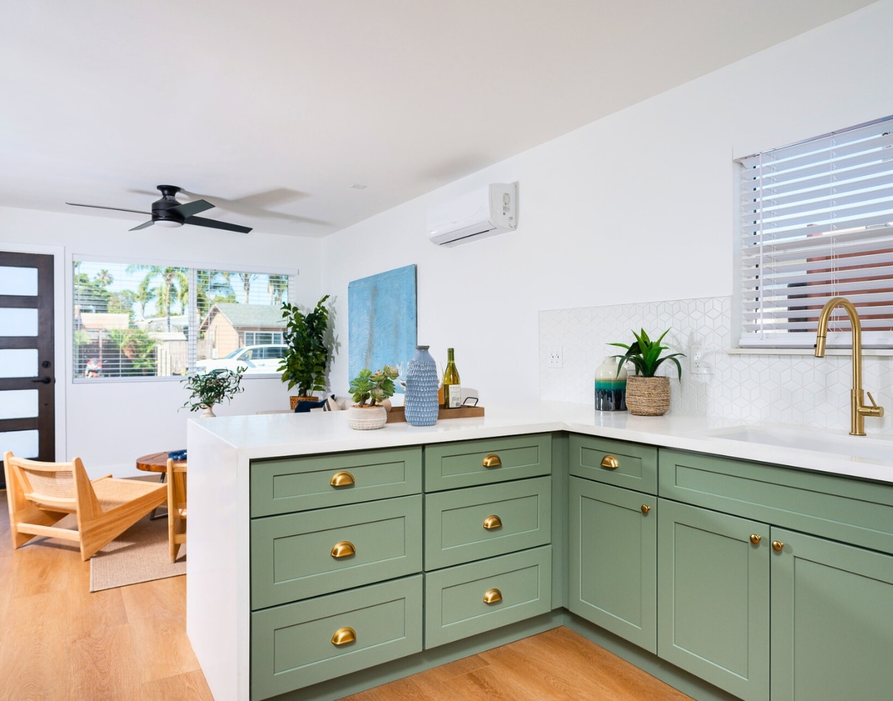 A stylish ADU kitchen featuring mint green cabinets, gold hardware, and natural wood flooring, demonstrating the benefits of ADUs by adding luxury and rental value to existing properties.