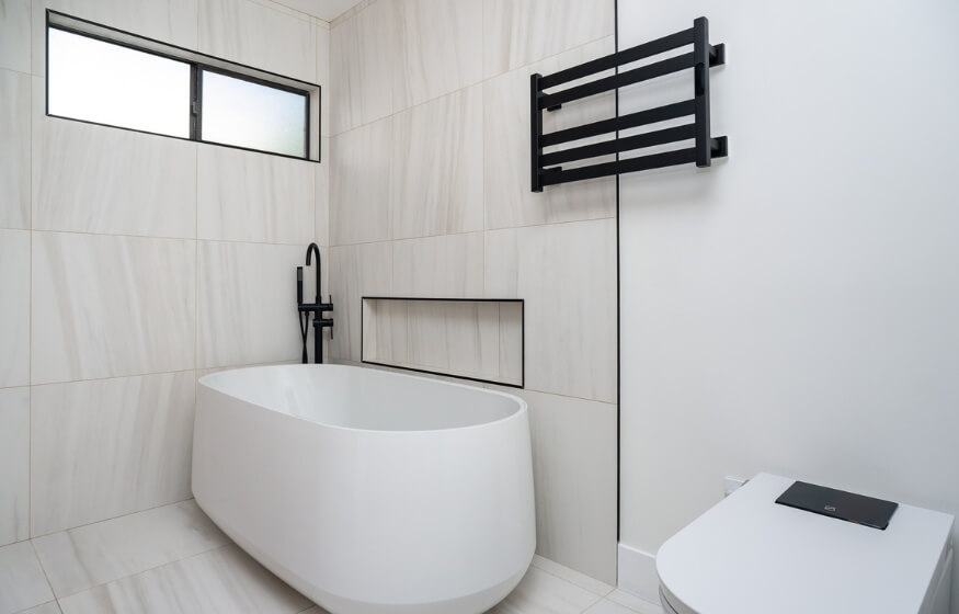 A modern, minimalist bathroom with a freestanding tub and sleek fixtures, demonstrating high-end ADU interior finishes in Imperial Beach.