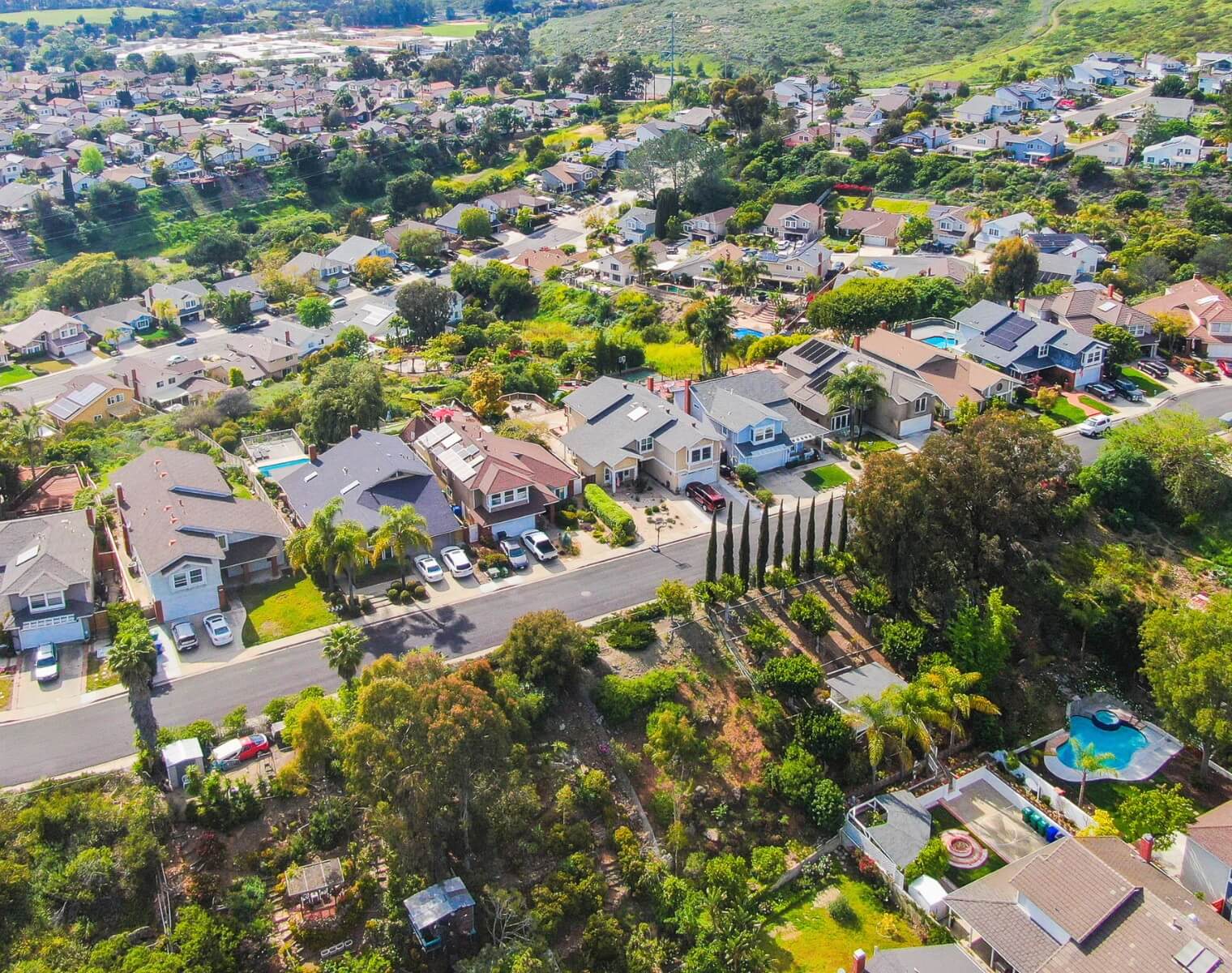 Scenic aerial view of a Rancho Santa Fe neighborhood showcasing homes, green landscapes, and rolling hills.