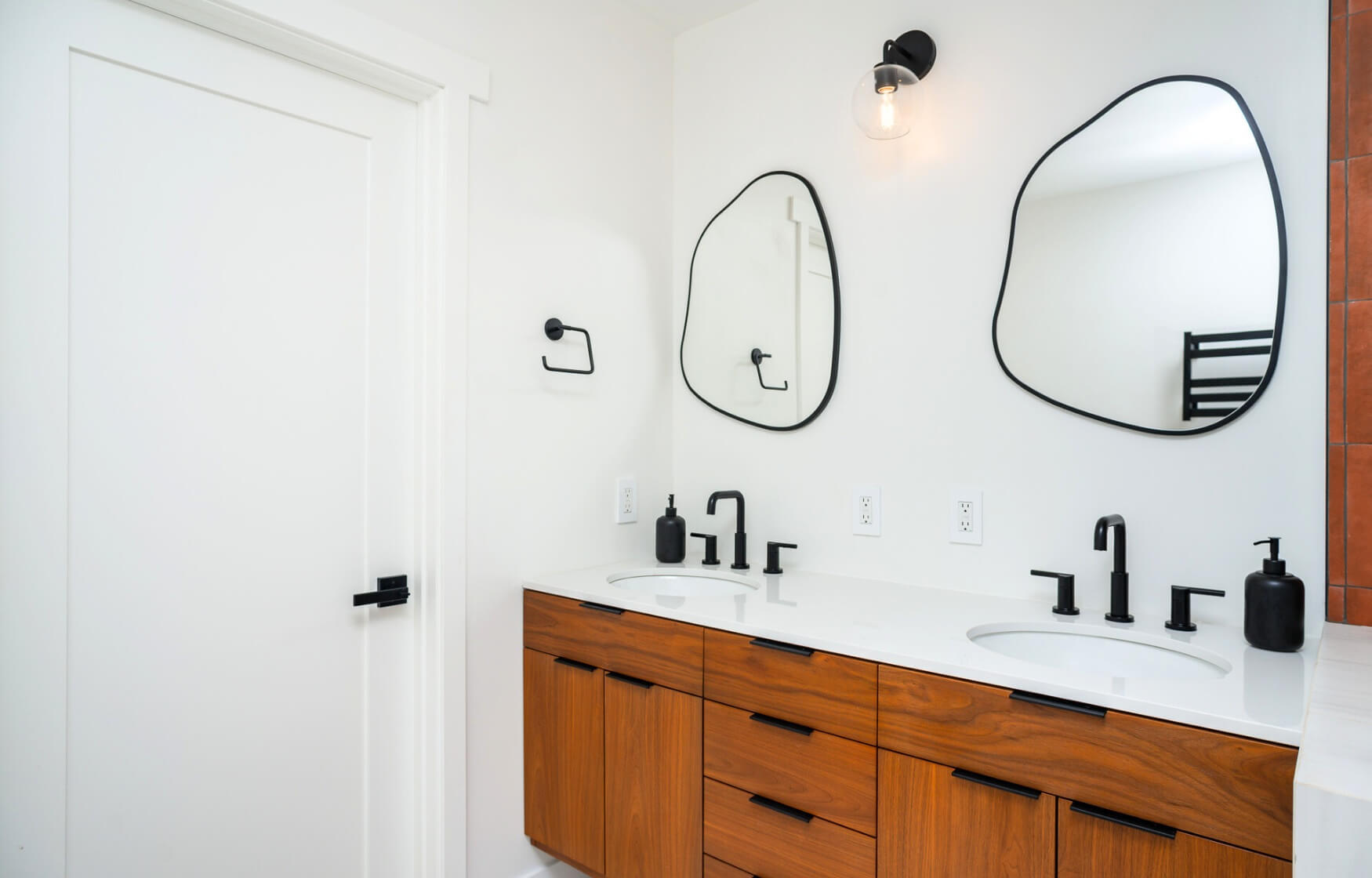 Modern ADU bathroom with stylish wood cabinetry, dual sinks, and unique mirror designs, offering a sleek and contemporary look.