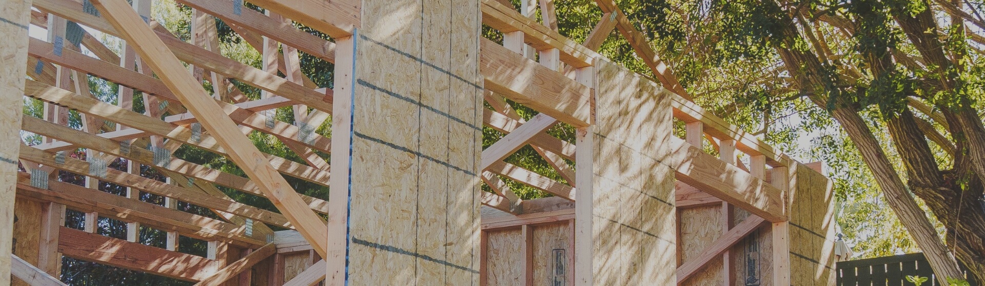 Framing stage of a room addition construction project for an ADU, showcasing wooden beams and structural detailing under natural sunlight.
