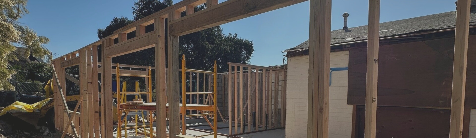 Close-up shot of an ADU structure in its framing stage, with construction materials and tools on-site.