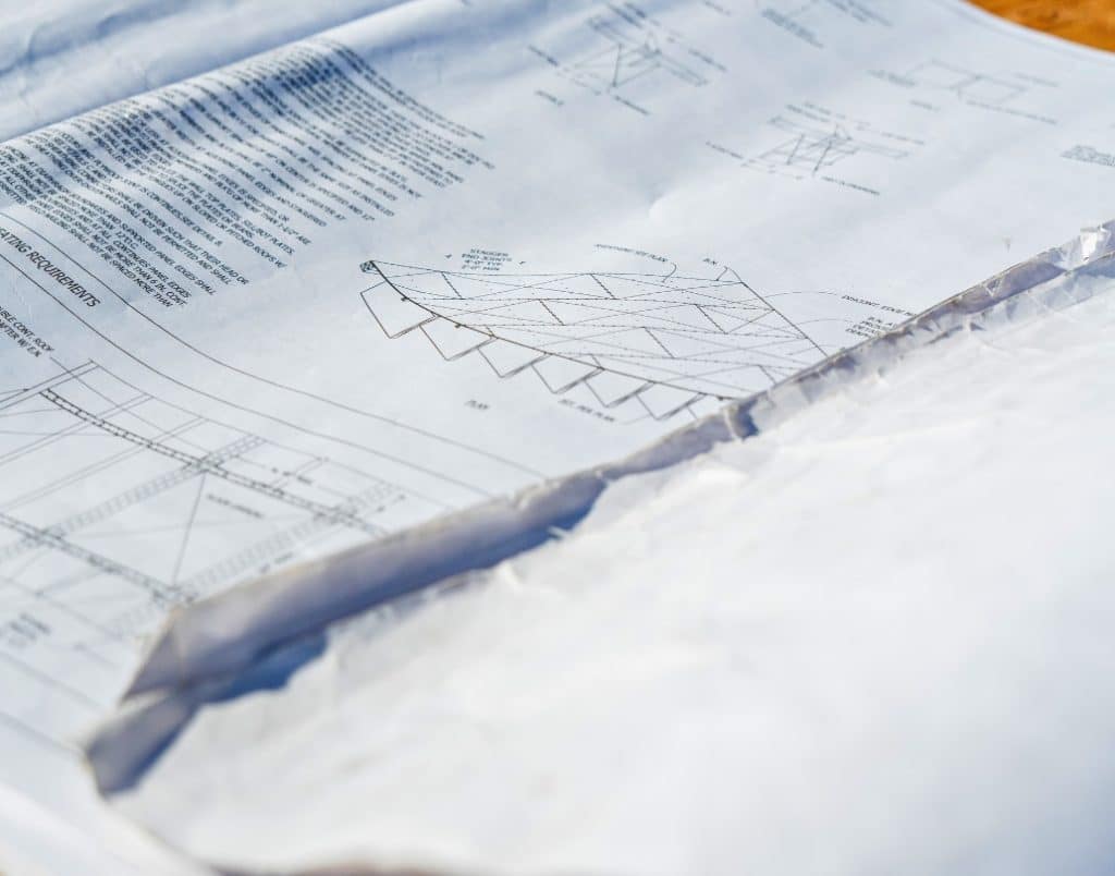 Detailed architectural blueprints spread out on a construction site, showing an ADU’s structural plans.