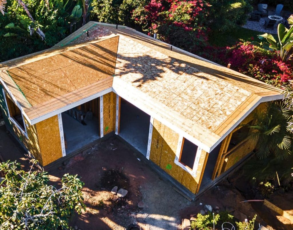 A nearly completed ADU structure in San Diego, showcasing wooden framing and open windows during the construction process.