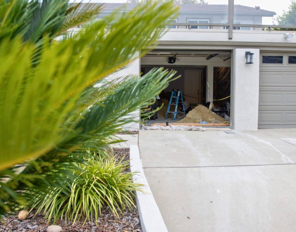 A garage undergoing conversion to an ADU, with visible construction tools and exposed wiring.