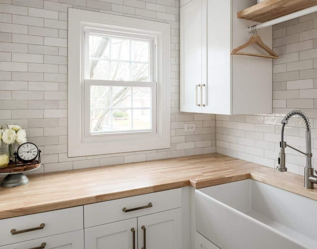 Custom cabinetry in a bright laundry room with wooden countertops and white tile backsplash.