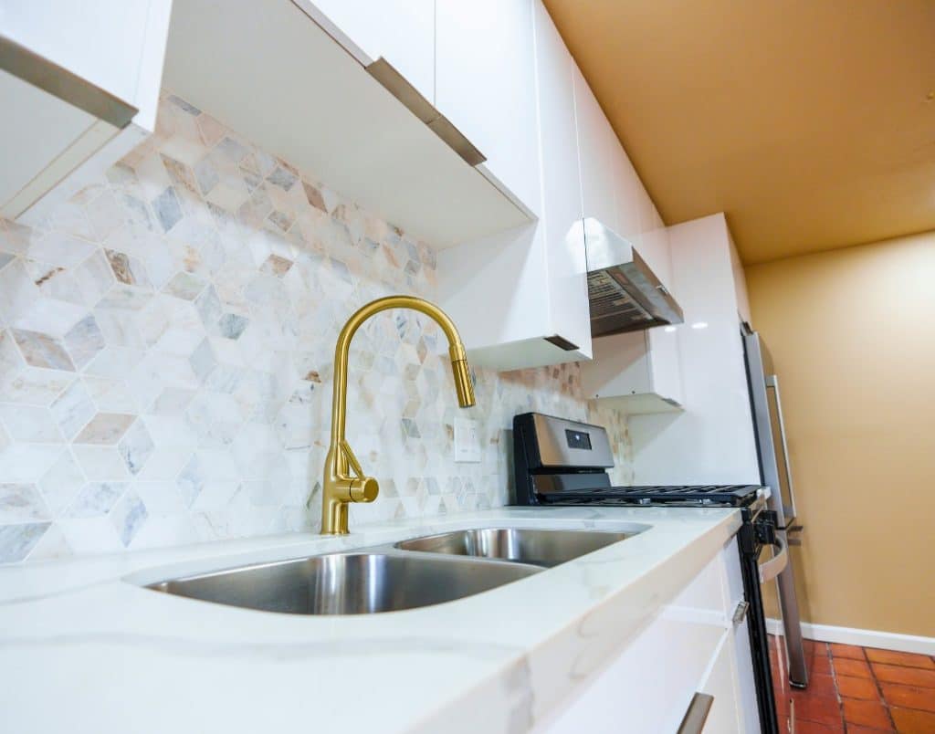 Modern kitchen with premium finishes, including a gold faucet and marble backsplash, illustrating interior finish options for ADUs.