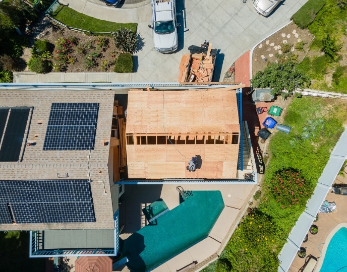 Aerial view of an ADU under construction next to a backyard pool, showcasing proximity to recreational areas. Demonstrates the feasibility and considerations when building an ADU near a pool, emphasizing planning around space, safety, and access requirements for harmonious integration.