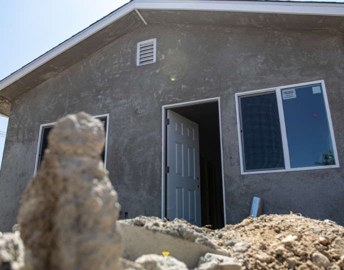 Exterior of a partially finished ADU, highlighting structural progress with a concrete finish and open doorway. Demonstrates the difference between a pool house and an ADU, as ADUs are fully equipped with utilities and designed for year-round living, unlike typical pool houses that serve as seasonal or recreational spaces.