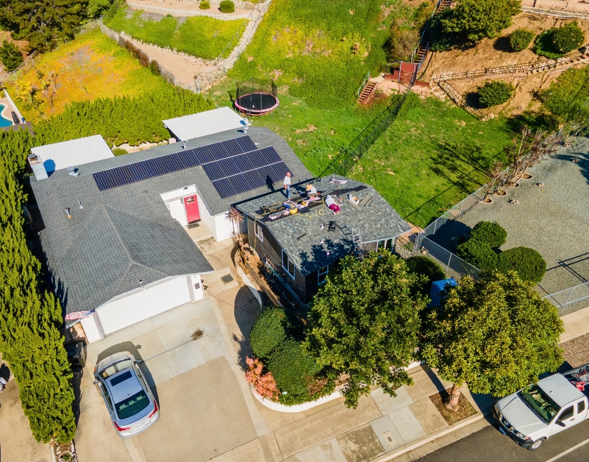 Aerial shot of a San Diego home with rooftop solar panels and construction work on a junior ADU, showcasing sustainable building practices.