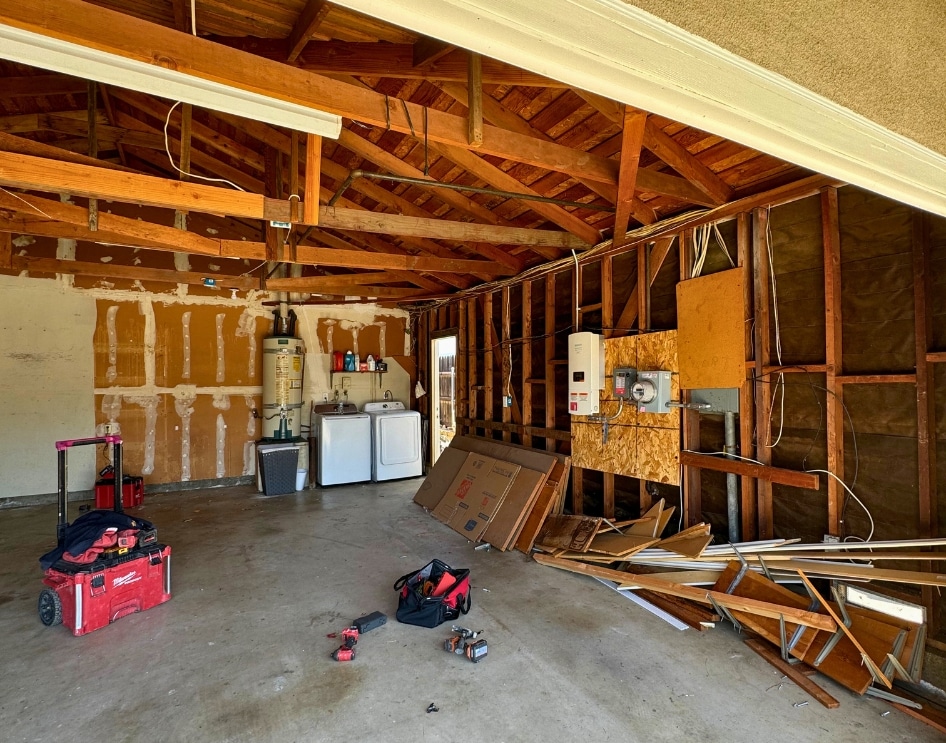 Garage conversion in progress, showcasing the early stages of an ADU construction with exposed framing and groundwork preparation. Highlights utility connections for ADUs in Greater San Diego, emphasizing the importance of integrating electrical, water, and sewage lines to meet residential standards for independent living spaces.