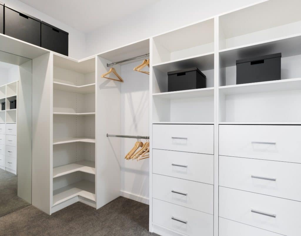 Modern white closet featuring open shelving and drawers for versatile storage solutions.