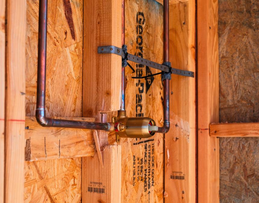 In-wall plumbing setup with water and drainage pipes installed, representing rough-in plumbing costs.