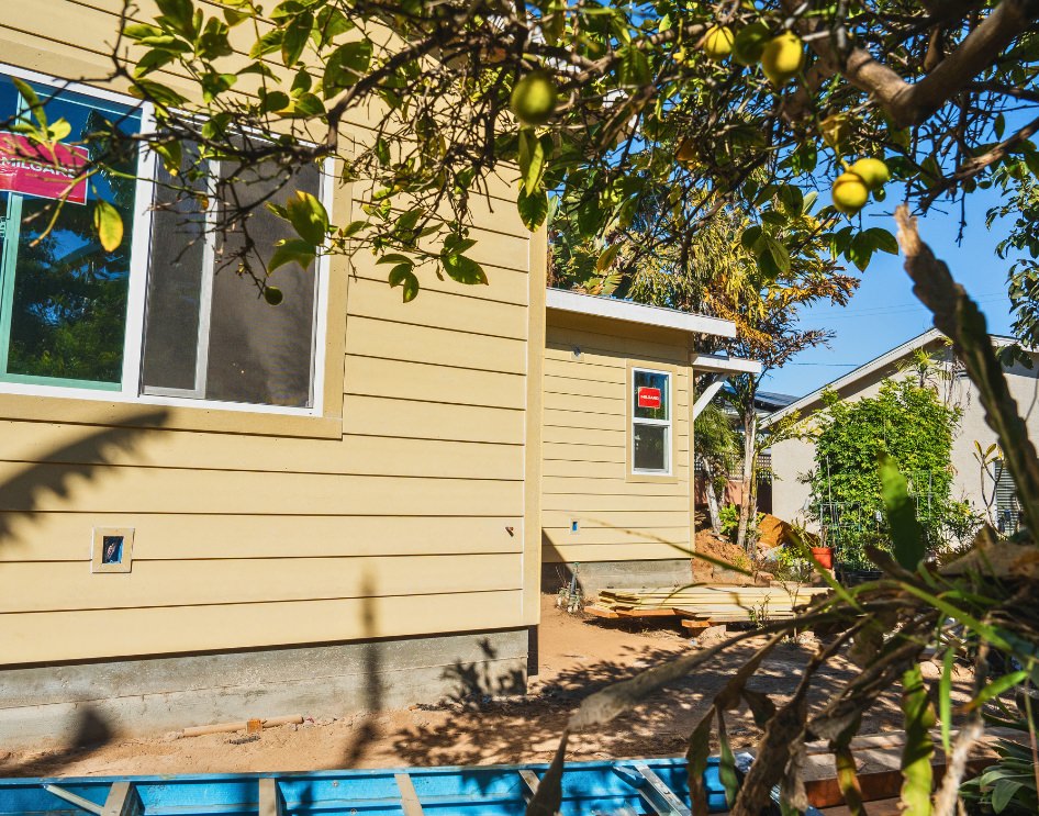 A nearly completed ADU with siding installation underway in a landscaped backyard, illustrating potential challenges from HOA restrictions.