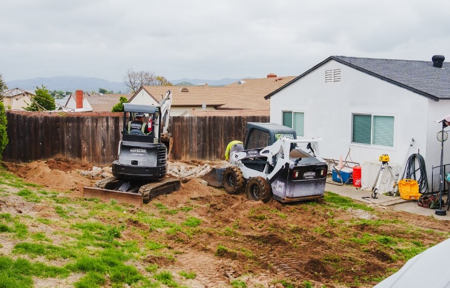 Backyard construction site with excavation equipment preparing the ground for an ADU build in San Diego – San Diego ADU Regulations Frequently Asked Questions