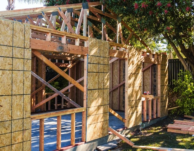Side yard view of an ADU under construction with minimal clearance from lot edge, representing reduced setback allowances – Setbacks & Coverage