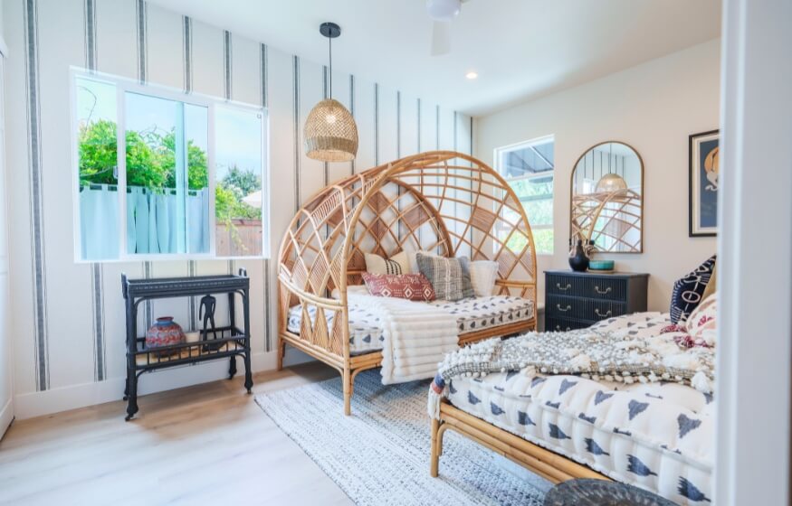 Boho-style bedroom inside a 400 sq ft ADU featuring twin rattan canopy beds, accent pillows, and natural light—ideal for illustrating compact floor plan versatility.