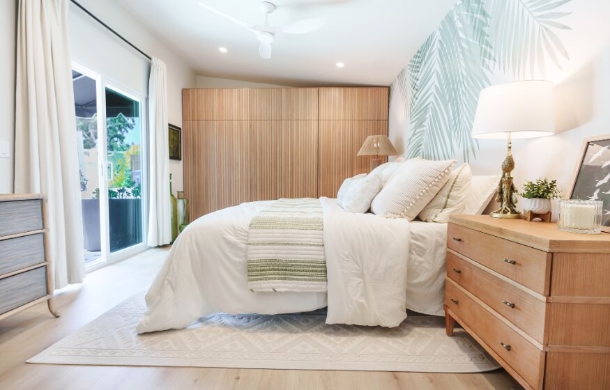 Bedroom interior of a 700 sq ft ADU with layered textures and accent wallpaper.