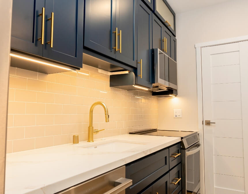 Interior view of a compact kitchen with blue cabinetry and gold hardware.