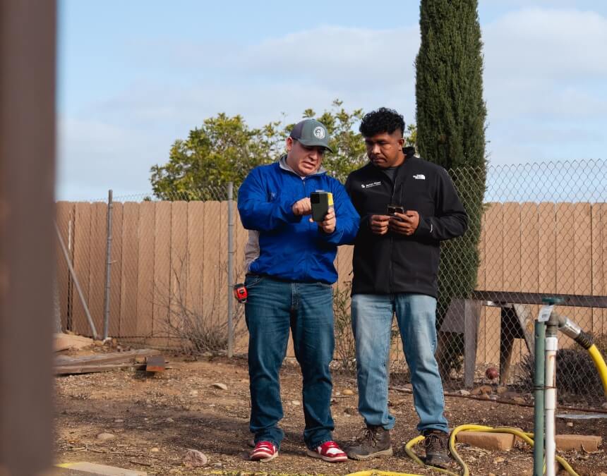 Two ADU professionals reviewing digital plans on-site near a project area