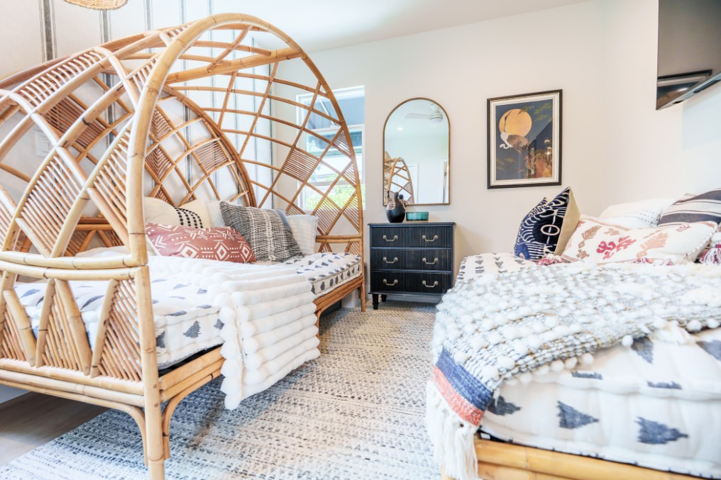 Cozy boho-chic guest room featuring a unique rattan canopy daybed, eclectic textiles, and earthy décor
