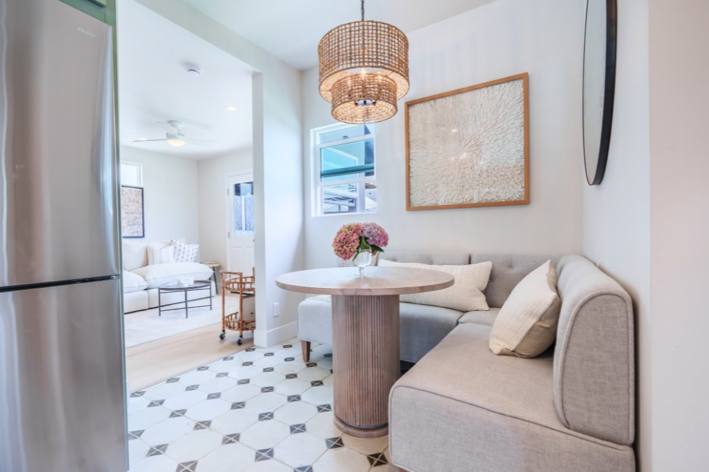 Intimate dining nook in detached ADU with upholstered seating, round wooden table, and woven pendant light