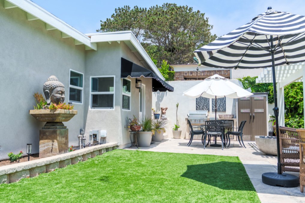 Boho chic ADU backyard with Buddha fountain, green turf, and stylish outdoor dining area