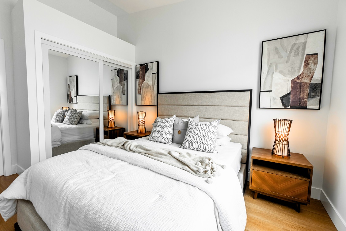 Modern ADU bedroom with upholstered headboard, mirrored closet doors, and neutral décor