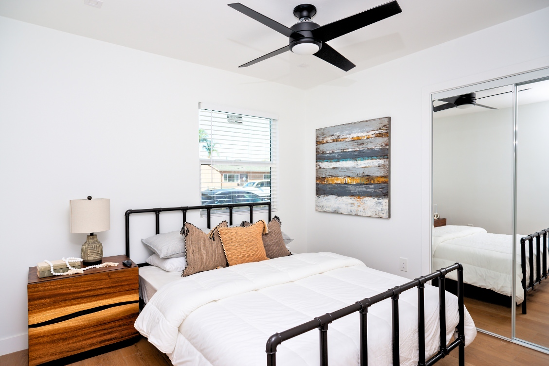 Cozy ADU bedroom with woven headboard, mirrored closet doors, and neutral bedding