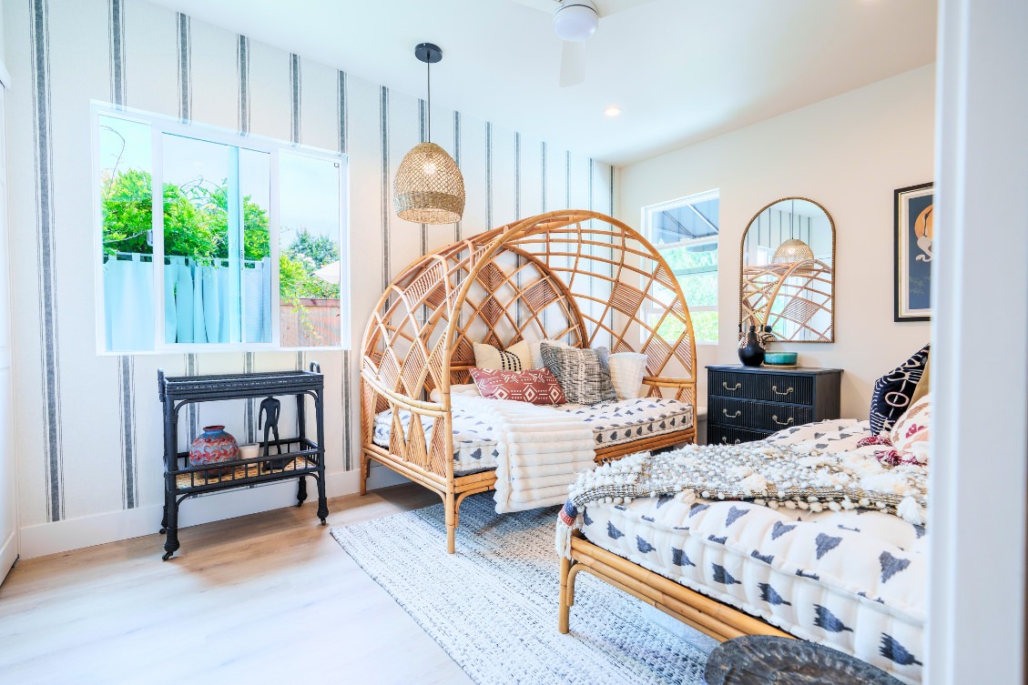 Boho-inspired ADU bedroom with rattan beds, patterned bedding, and pendant lighting