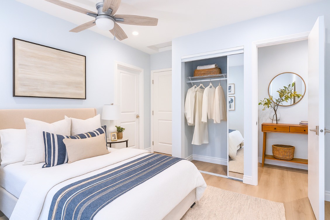 Cozy ADU bedroom with blue and white striped bedding, mirrored closet, and ceiling fan