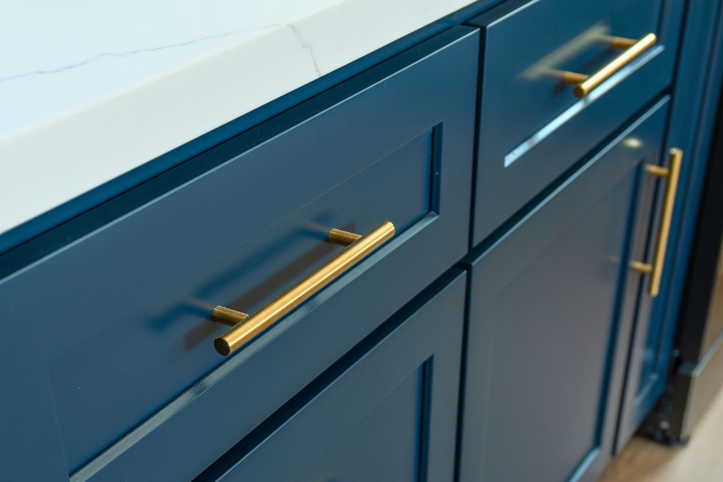 Close-up of navy kitchen cabinetry featuring elegant gold handles in attached ADU kitchen.
