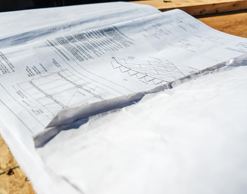 Close-up of architectural construction blueprints laid out on a wooden workbench.