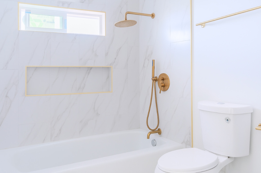 Contemporary bathroom showcasing marble tiles, bathtub, and luxurious gold shower fixtures