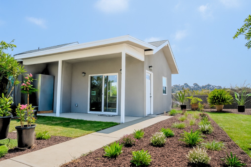 Front exterior view of modern coastal detached ADU with vibrant landscaping and covered patio