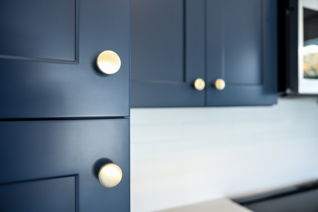 Close-up of modern navy-blue kitchen cabinetry accented with gold knobs in detached ADU.