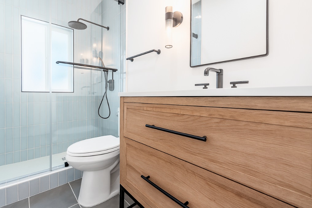 Stylish bathroom with glass-enclosed shower, modern fixtures, and wooden vanity in coastal ADU