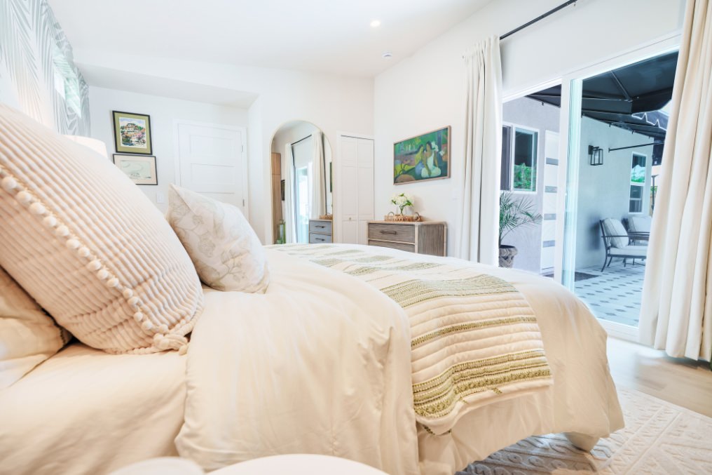 Cozy and inviting boho bedroom with neutral textiles, calming décor, and views toward private patio in ADU