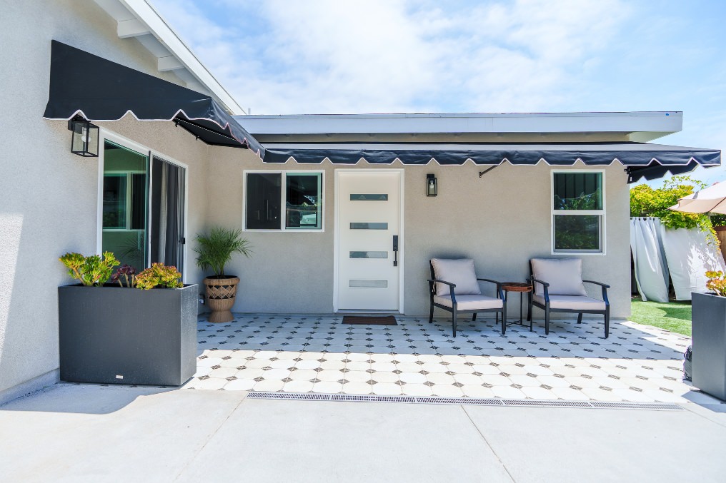 Inviting patio seating area with geometric tiles, awning, and minimalist décor at detached ADU