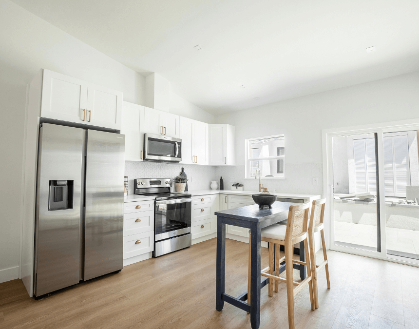 Modern ADU kitchen interior with energy-efficient stainless steel appliances, LED lighting, and natural daylight streaming through sliding glass doors.
