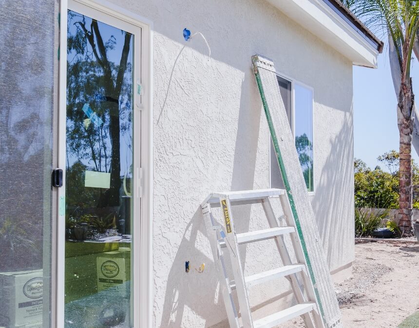 Exterior side of a stucco ADU under construction with a ladder leaning against the wall.