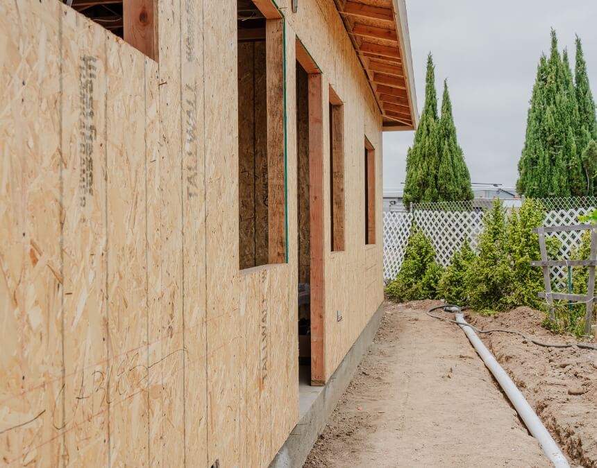 Exterior side view of an ADU in early framing and sheathing stage, with visible plywood and roof eaves.