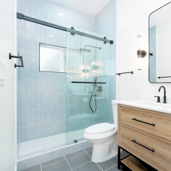 Contemporary ADU bathroom with walk-in shower and wood vanity built by trusted San Diego ADU builders.