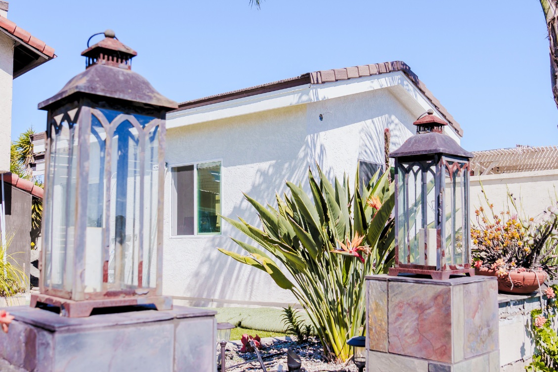 Backyard ADU with white stucco exterior, tile roof, and tropical landscaping