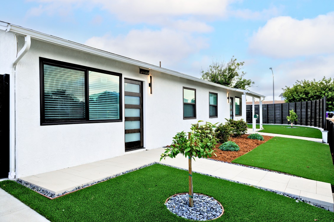 Contemporary ADU exterior with white stucco, black framed windows, and landscaped walkway