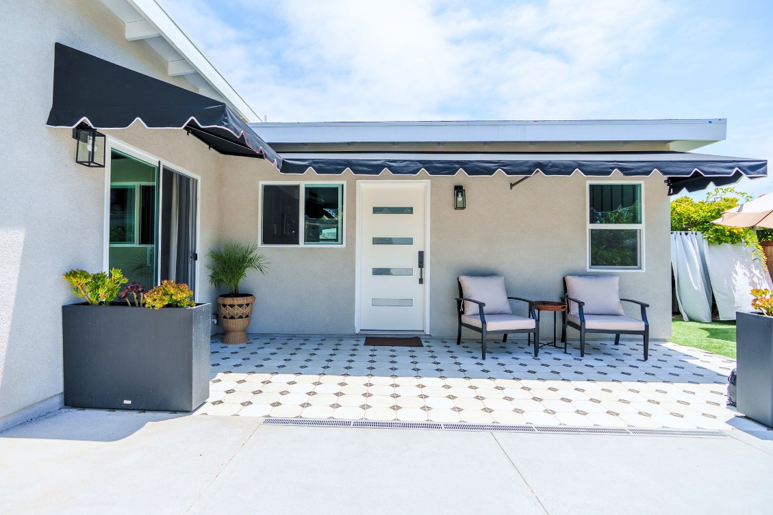 Front porch of an ADU with black awning, white modern door, and outdoor seating