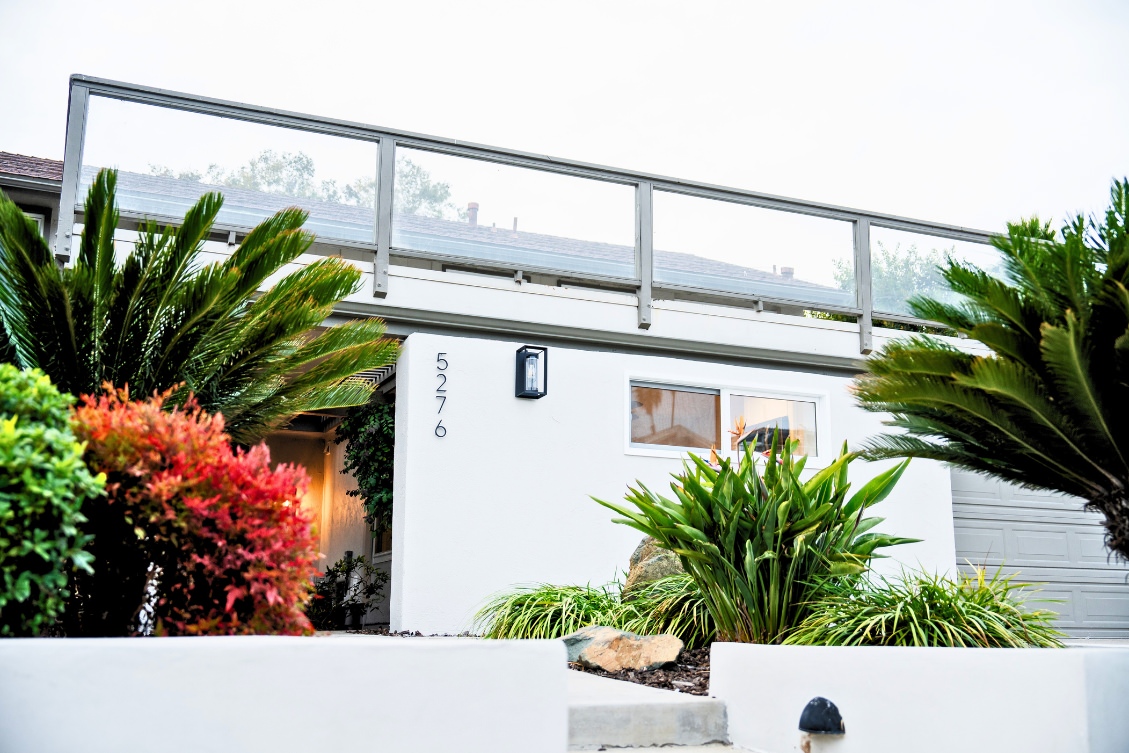Minimalist ADU exterior with white stucco, lush greenery, and modern windows