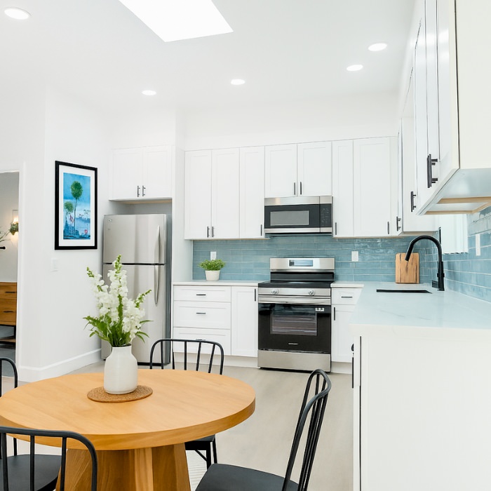 Stylish ADU kitchen with white cabinets and blue backsplash created by expert San Diego ADU builders.