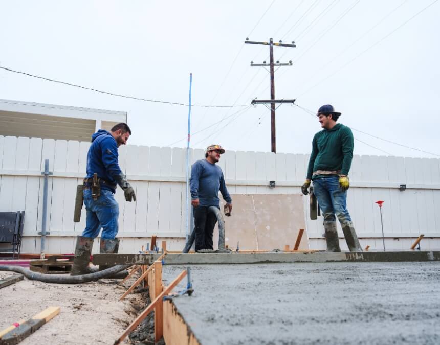 Differences Between Private and Public Projects featuring contractors pouring concrete foundation