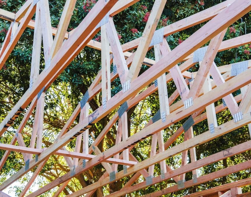 How do materials influence ADU durability and price – close-up of engineered wood roof trusses during framing.
